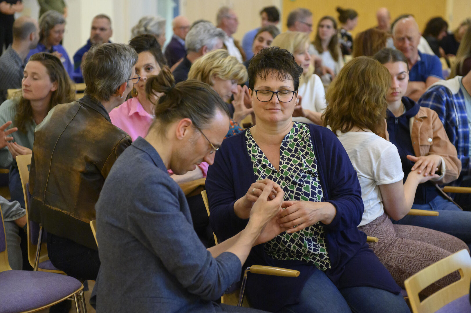 Publiek met ogen dicht en handen tegen elkaar